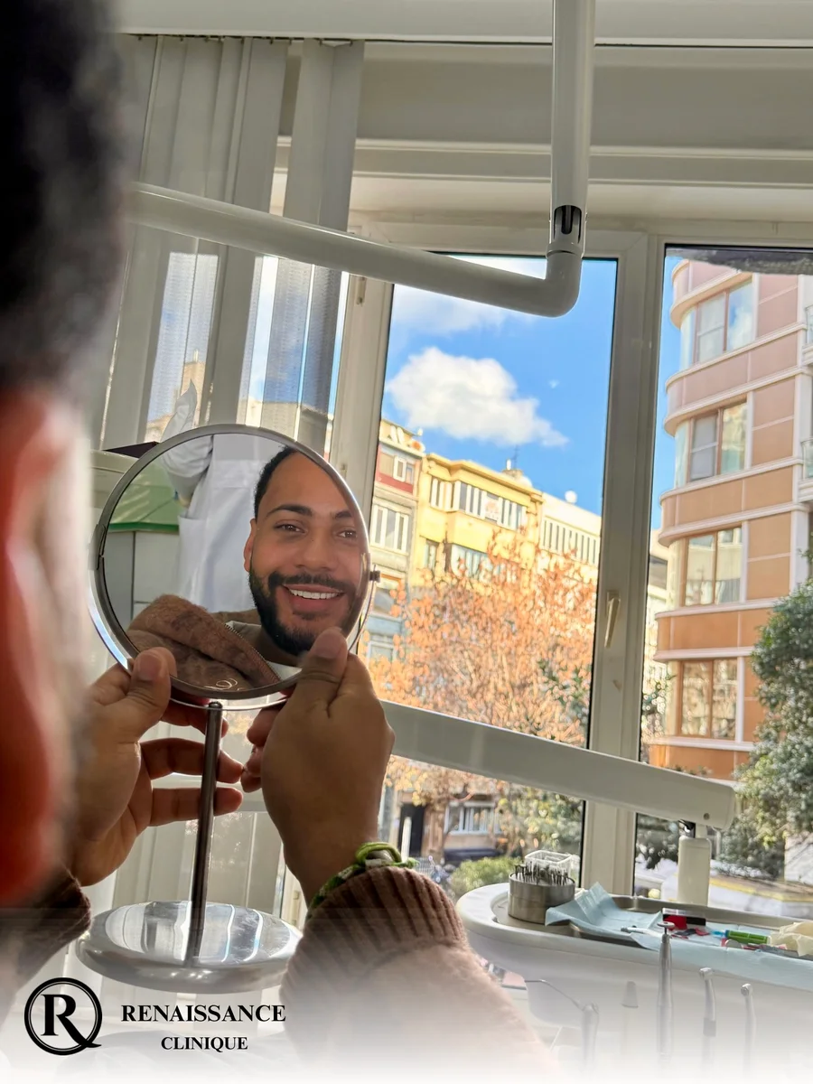 Nico Là découvre son nouveau sourire dans un miroir, face à une fenêtre donnant sur Istanbul